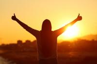 silhouette of person standing in sunset with thumbs up